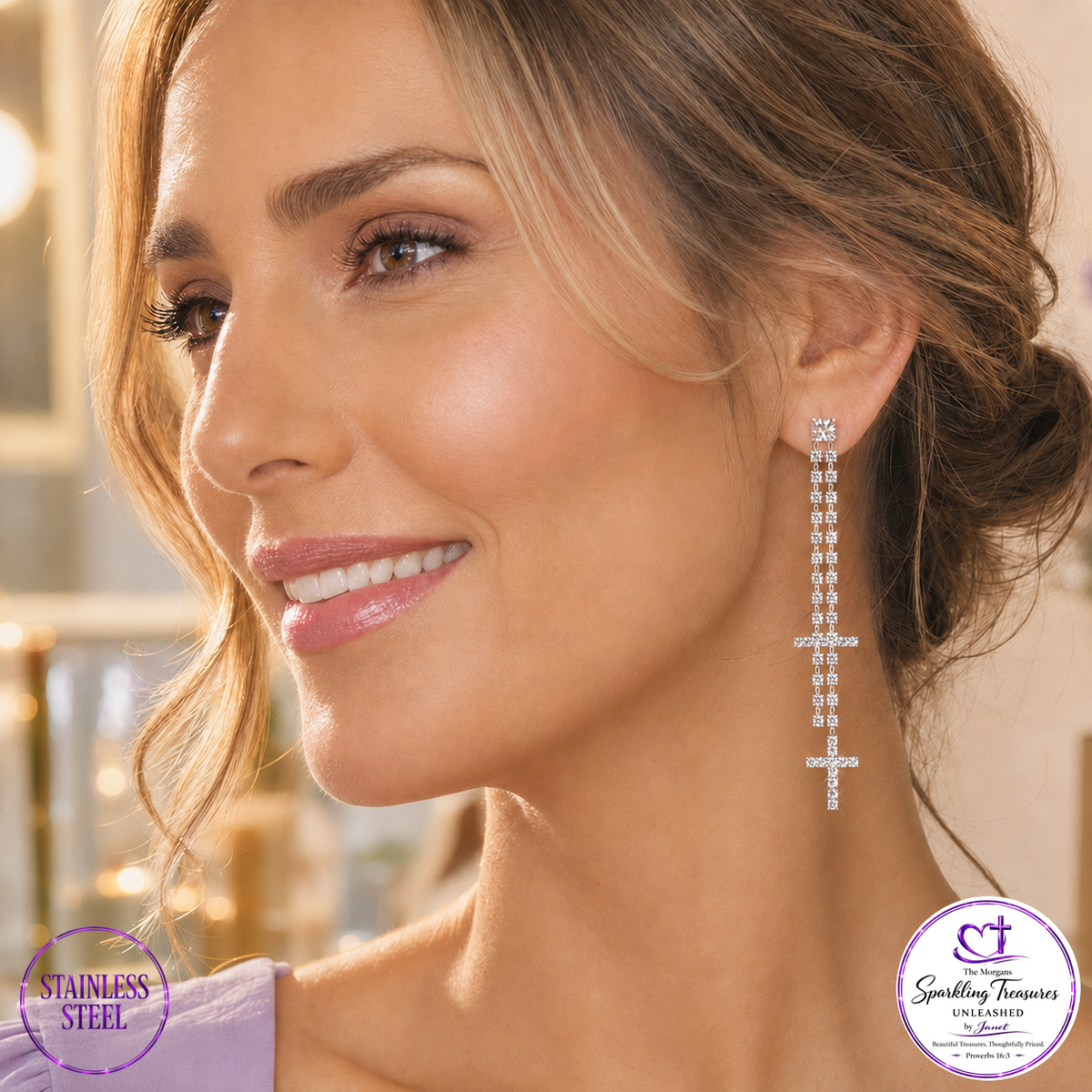 A woman in profile wearing a long drop earring made of silver-toned metal and clear stones. The earring features a small cross at the top with a cascading chain of rectangular and round clear stones ending in a cross.