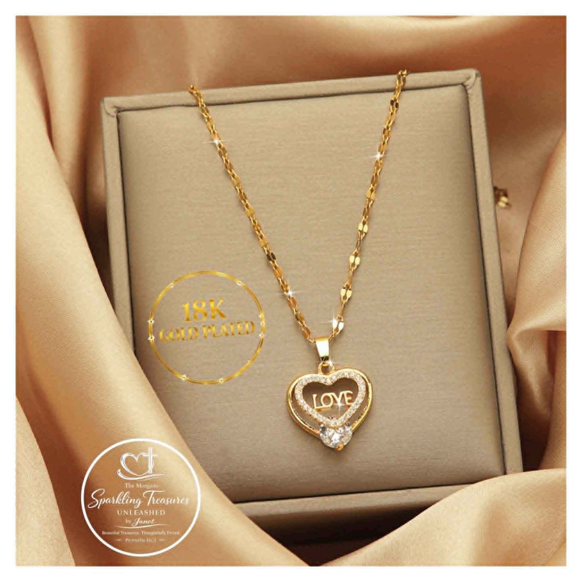 Gold necklace with heart-shaped pendant and 'LOVE' engraving on a beige box, brand 'INK Gold Plating' visible.
