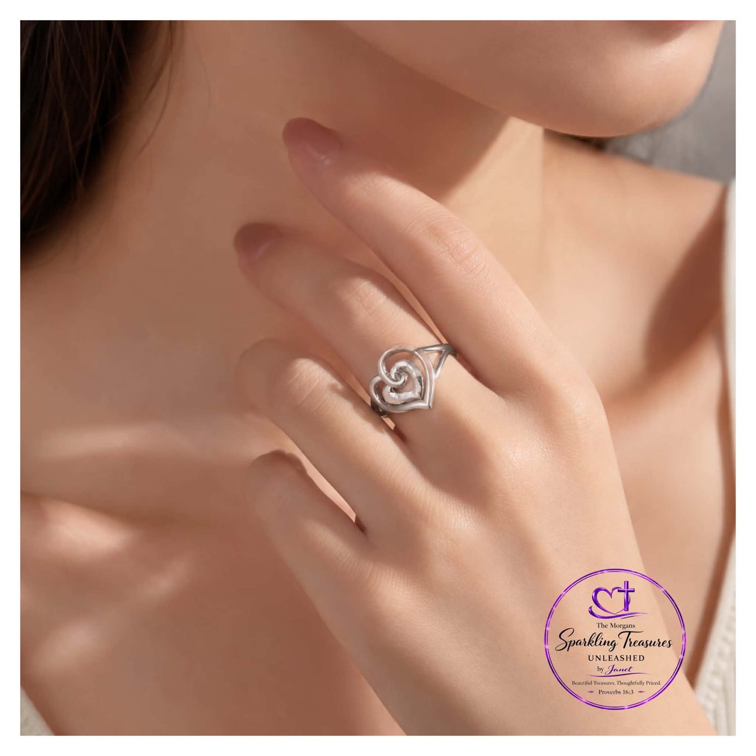 Silver heart-shaped ring on a model's finger with 'Sparkling Treasures' branding.