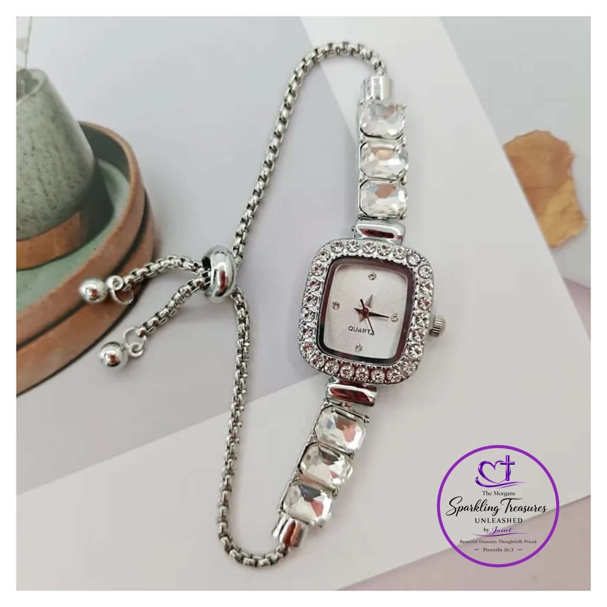 Silver watch with gemstone accents on a white surface, branded 'Sparkling Treasures'.