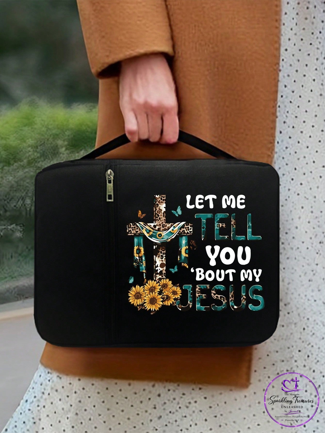 A person in a brown coat holds a black zippered case featuring a decorative cross, sunflowers, and the text 'LET ME TELL YOU ABOUT MY JESUS' in white and teal lettering.
