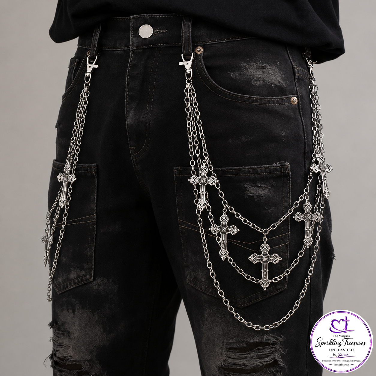 Distressed black denim jeans with multiple silver chain straps and cross pendants hanging from the back pockets, shown on a model against a light gray background.