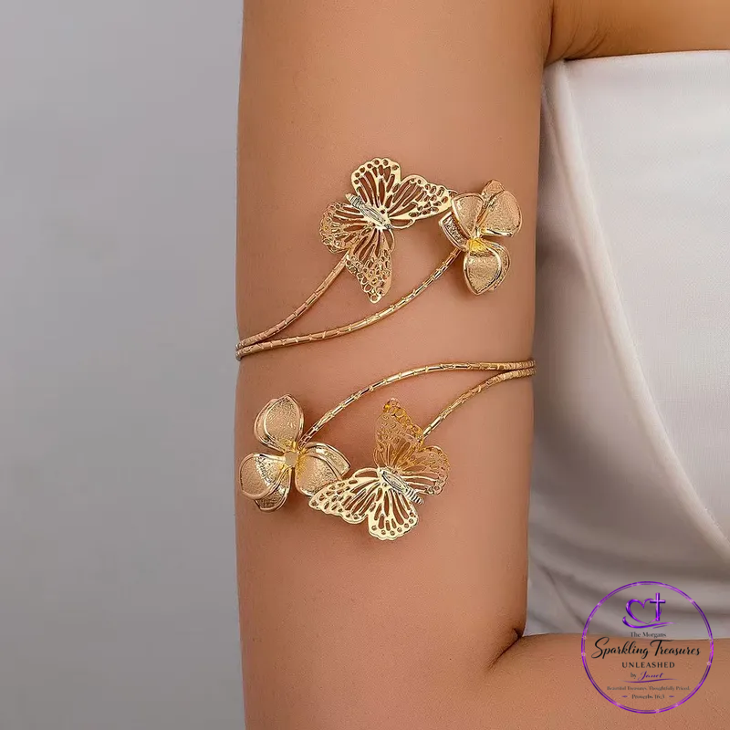 A gold-toned double-wrap arm cuff bracelet decorated with butterfly and flower motifs, shown worn on a person's upper arm.
